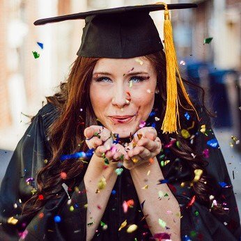 Graduate Student Greatness featured Image shows a woman in graduation regalia blowing a handful of confetti at the camera.