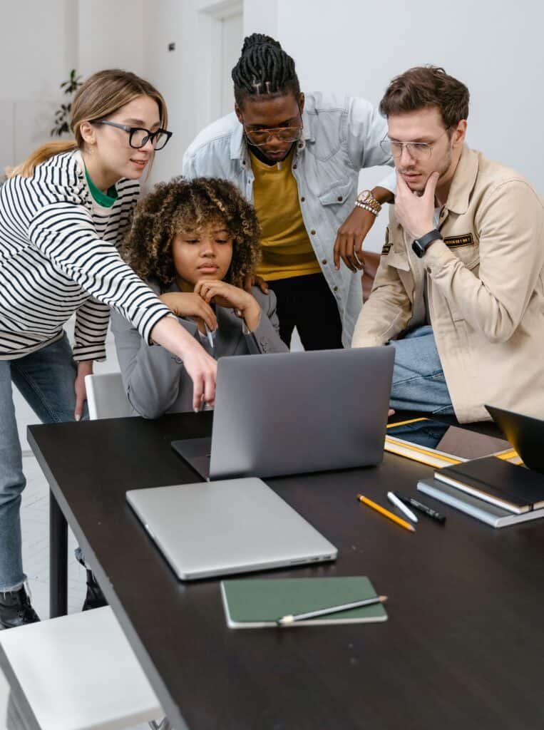 Image of a group of graduate students looking at a laptop together.