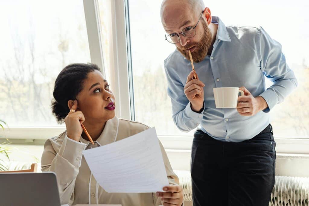 Research advisor looks down at a piece of paper being held up by their graduate student.